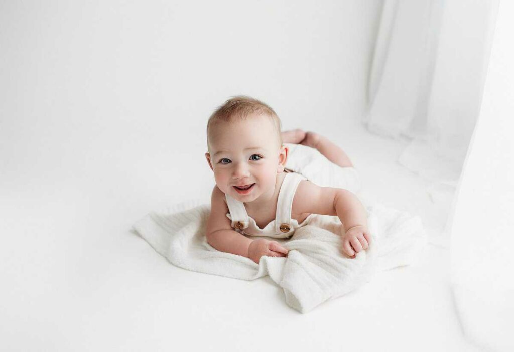 baby boy laying on his stomach in atlanta photography studio for his milestone portraits, outfits provided photography studio, atlanta baby photographer, baby smiling at photoshoot, baby photo session in georgia