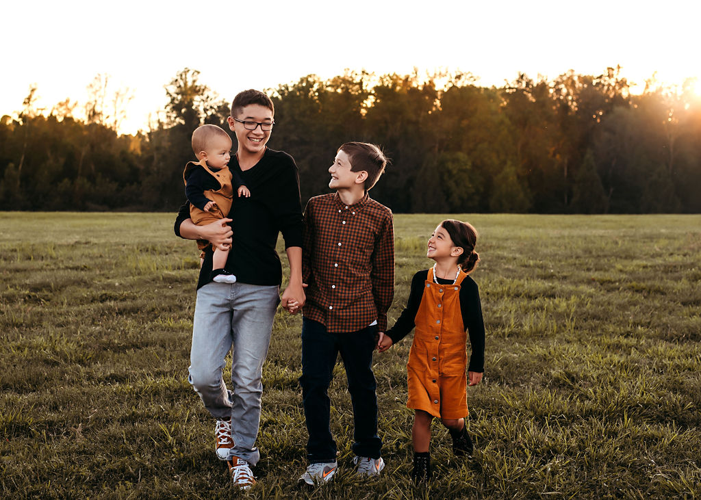 siblings smiling with eachother while walking during photography session in waverly nebraska, best family photographers nebraska
