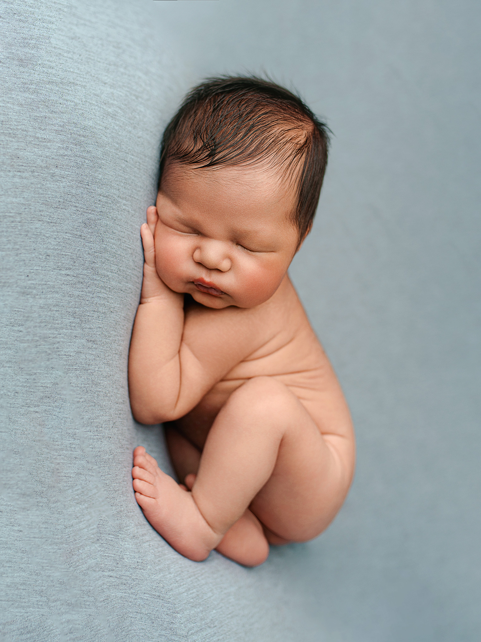 Newborn baby boy cuddled on blue, Omaha Nebraska photography session