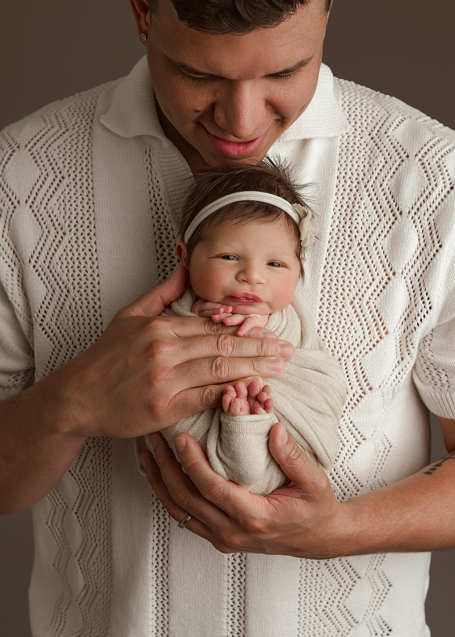 awake baby girl with floral headband in dads hands, captured by Nebraska newborn photographer