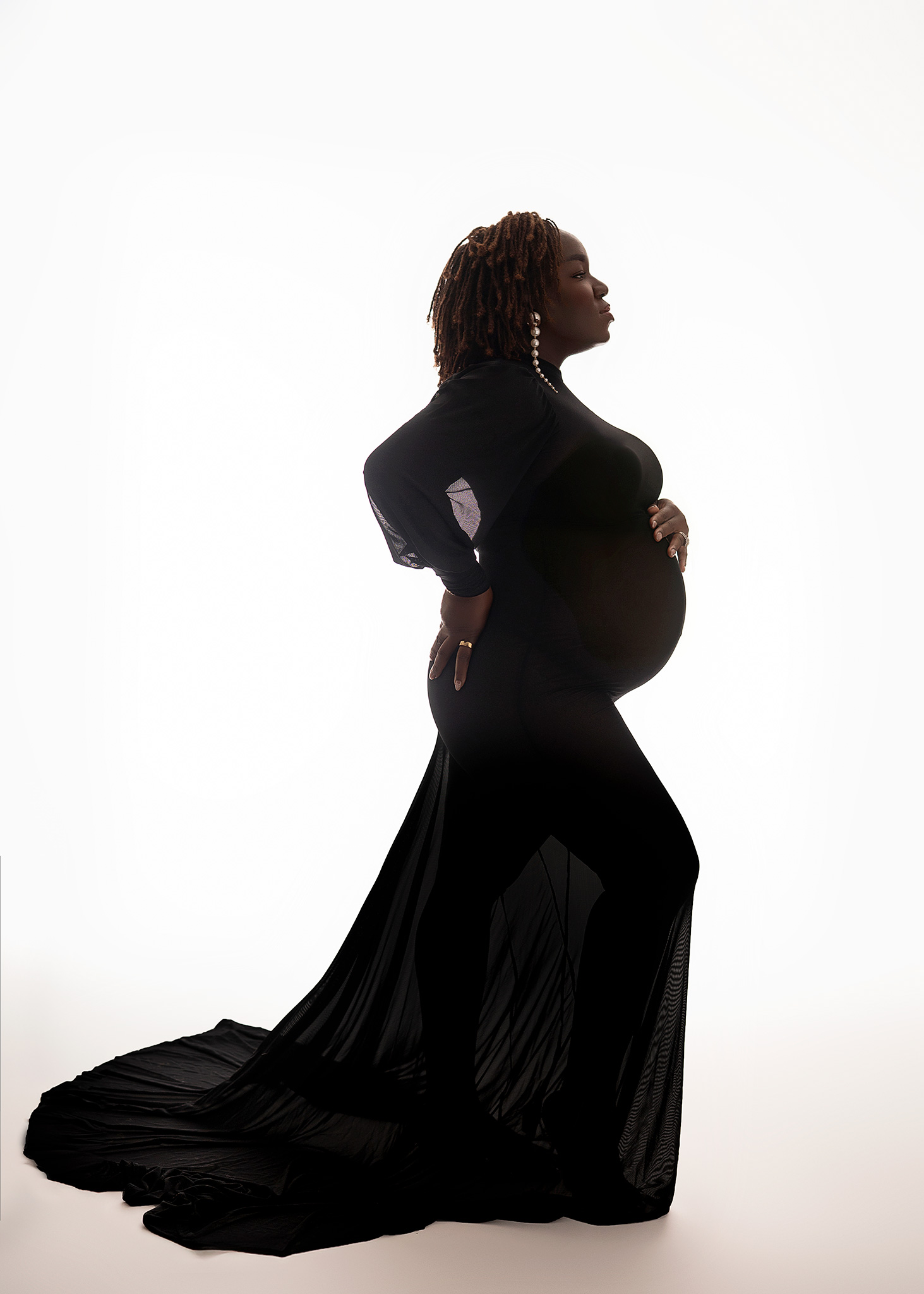 mom to be posed with a light backdrop, backlit maternity photos, darker toned mom to be posed for professional photoshoot, silhouette maternity poses