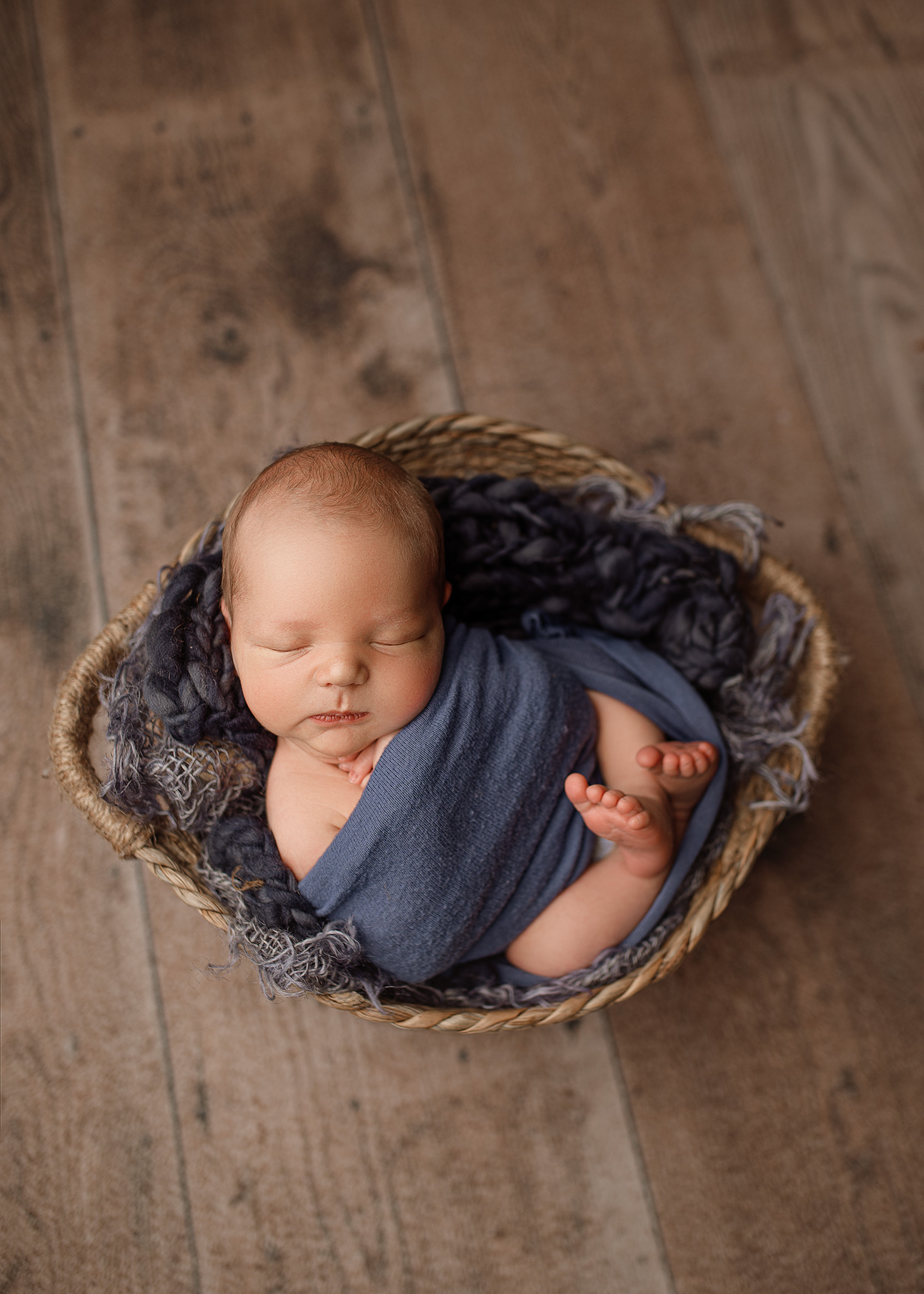 newborn boy in blue professionally photographed in nebraska studio