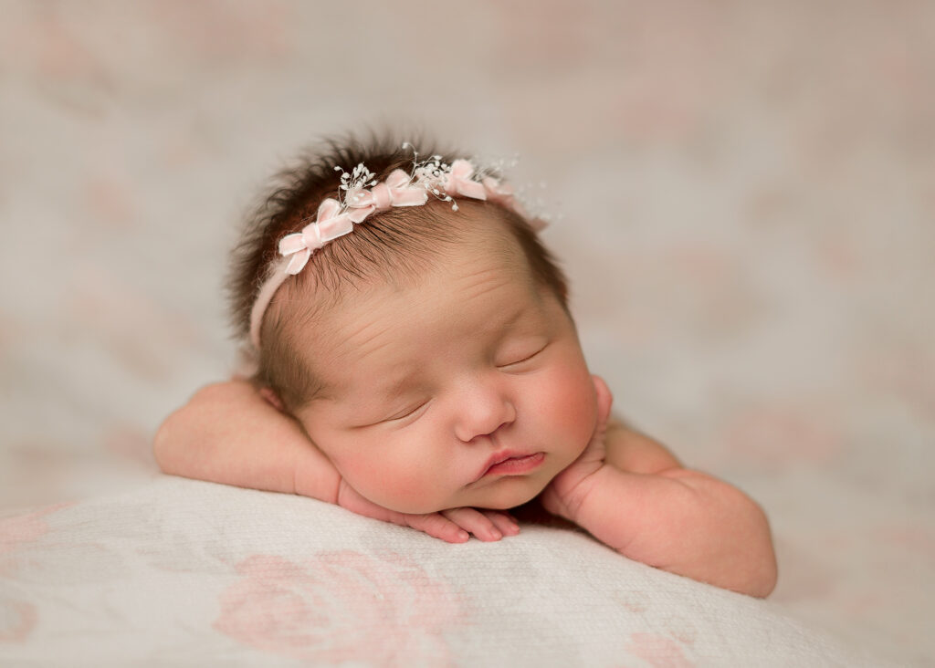 newborn baby girl on a pink floral fabric posed for her newborn session in nebraska